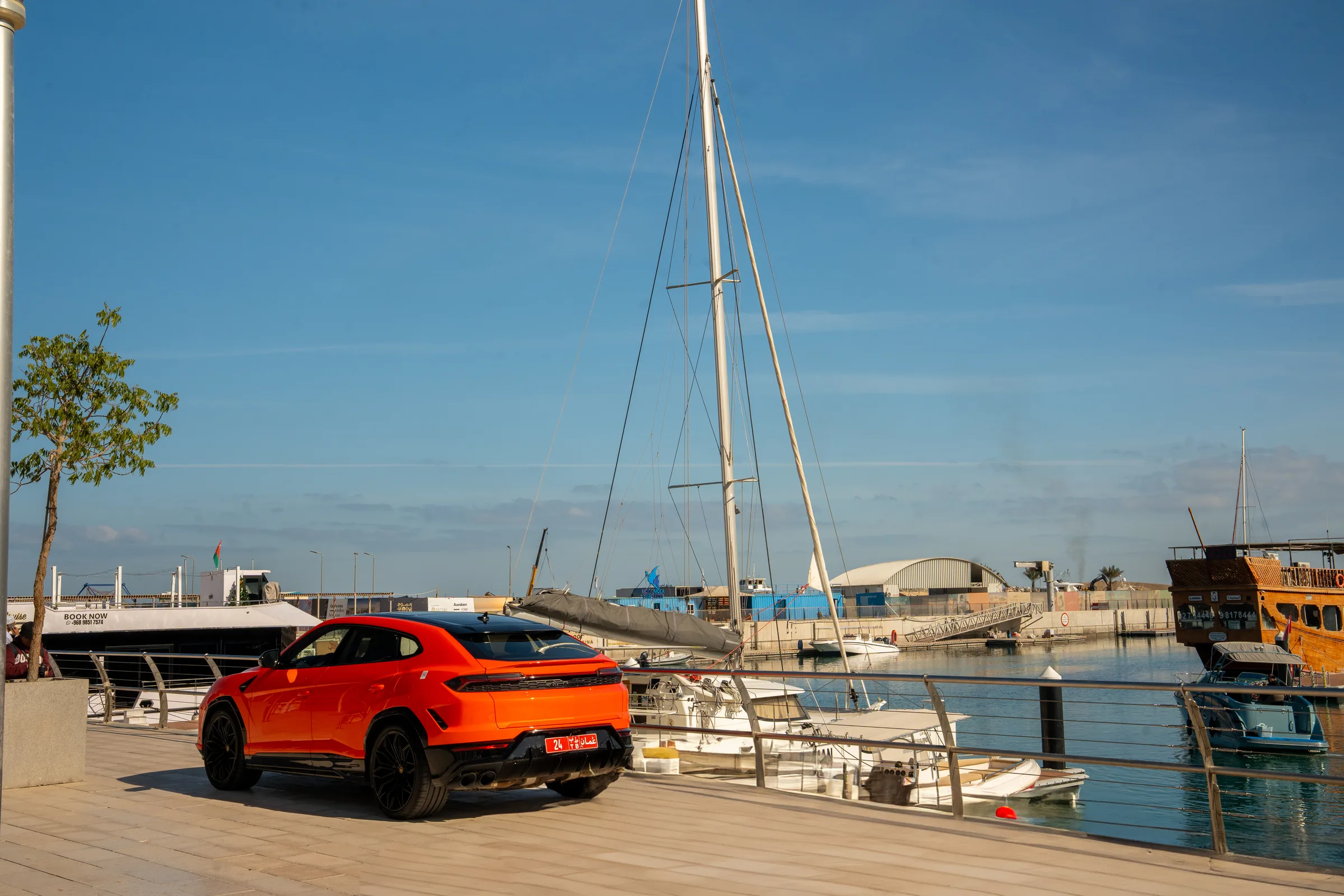 Lamborghini Urus rear quarter view at Al Mouj Marina with a traditional dhow boat