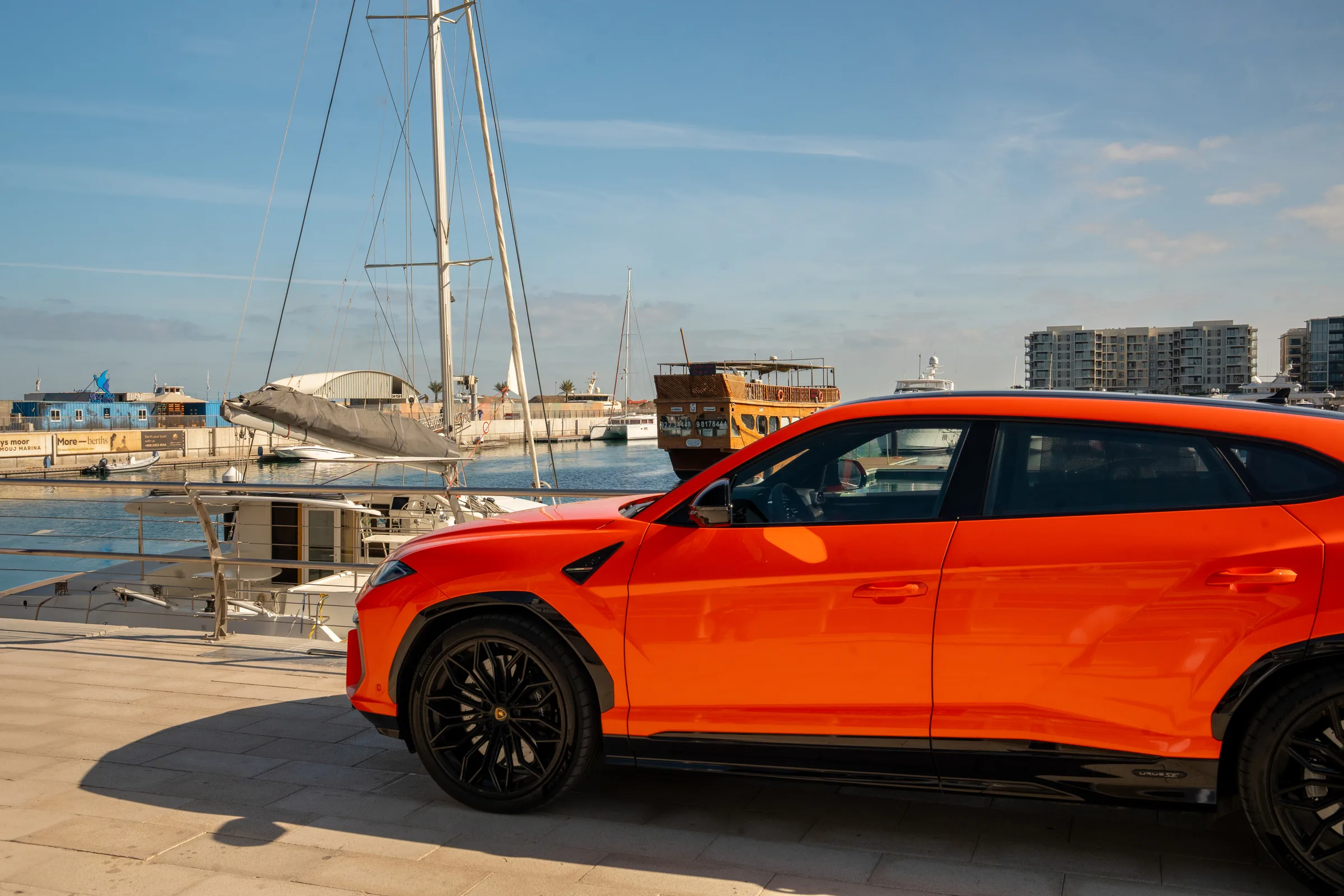 Lamborghini Urus side profile at Muscat marina with yachts