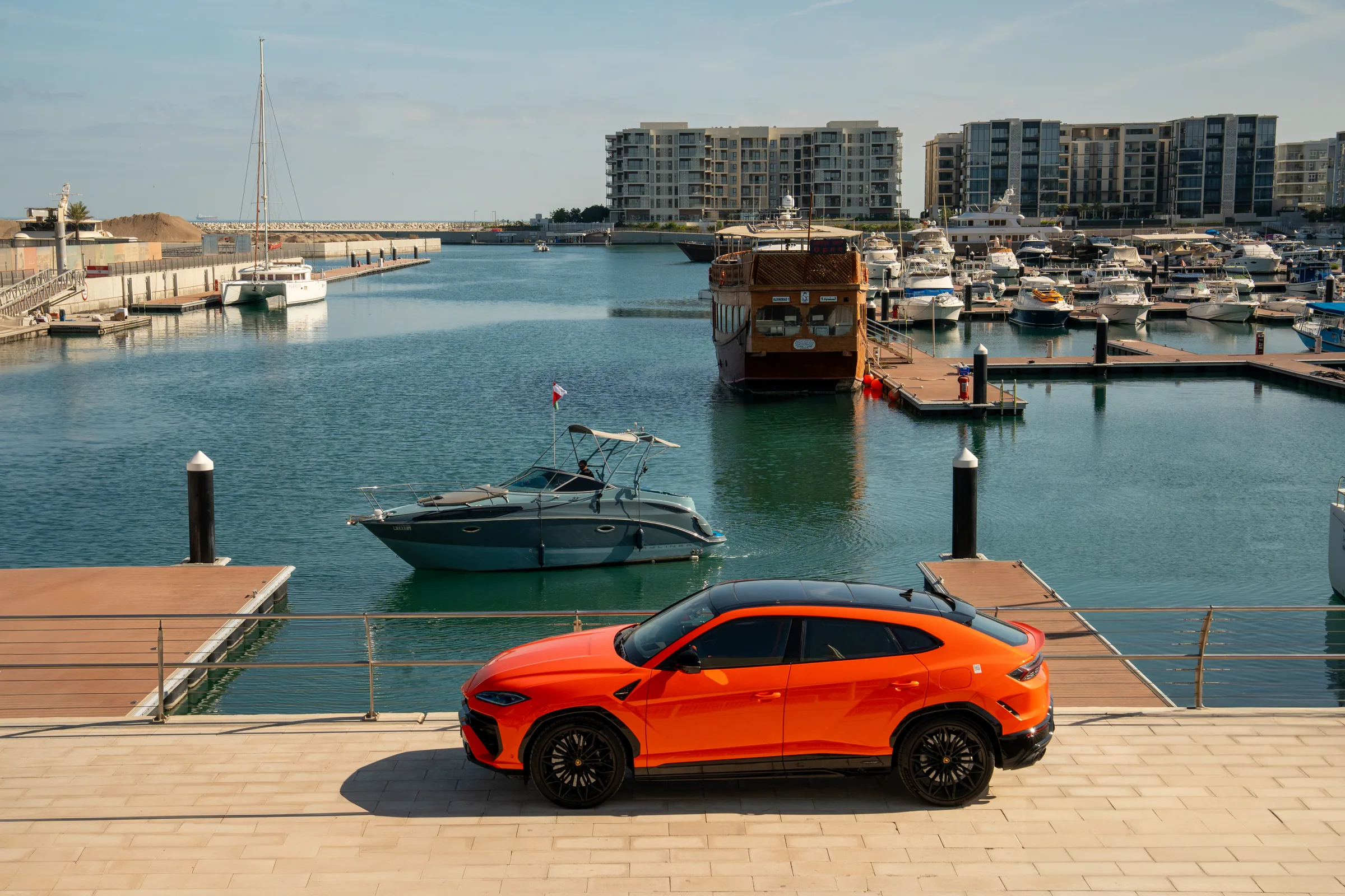 Lamborghini Urus parked at Al Mouj Marina with apartment buildings backdrop
