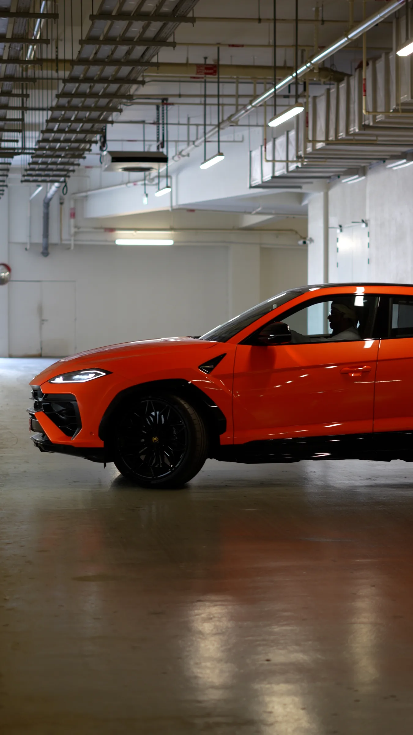 Lamborghini Urus side profile in a parking garage with driver